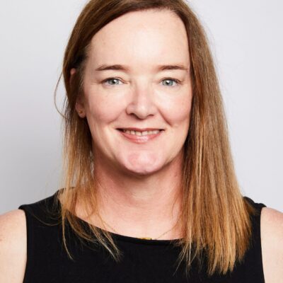 A professional headshot of a smiling woman wearing a black top