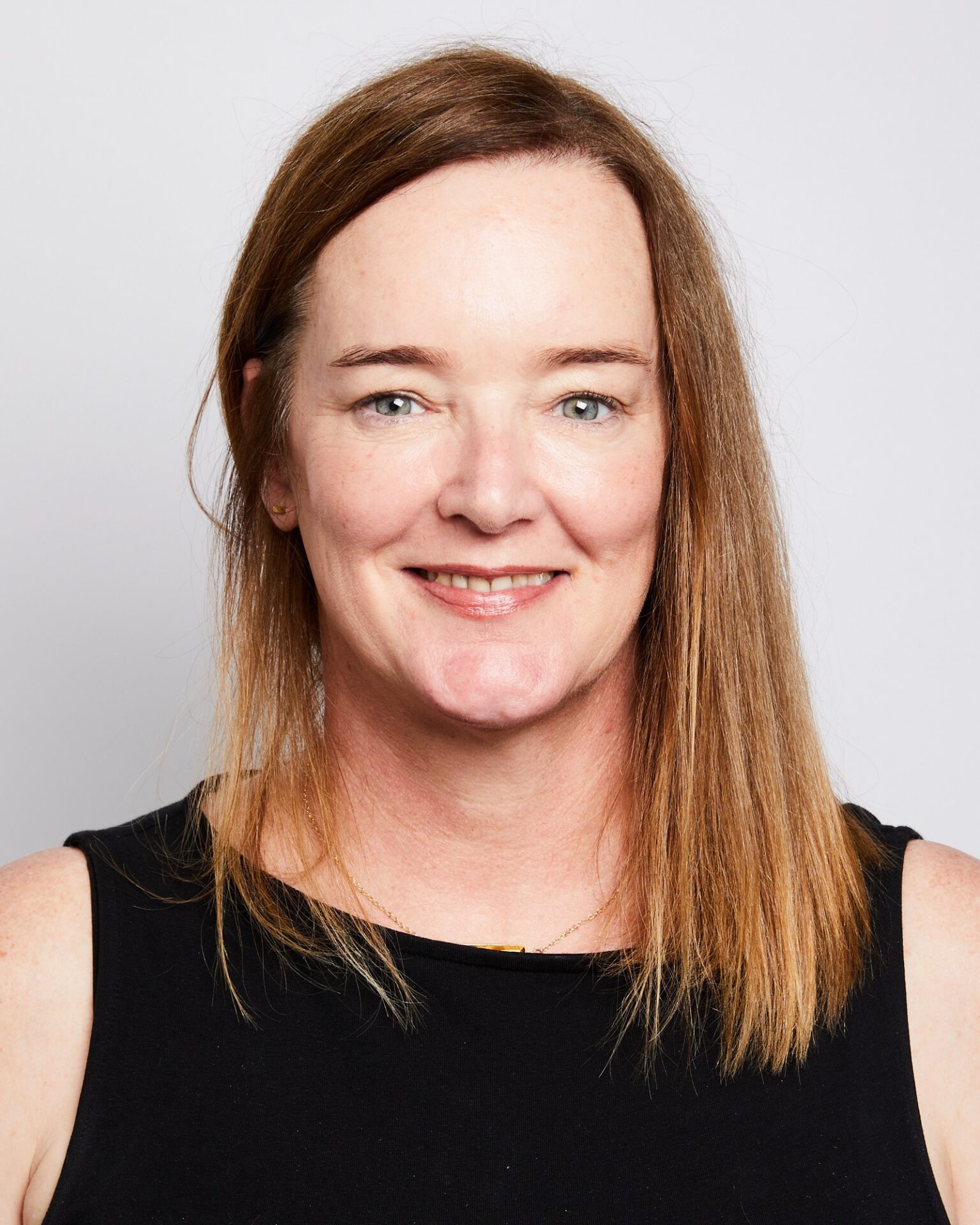 A professional headshot of a smiling woman wearing a black top