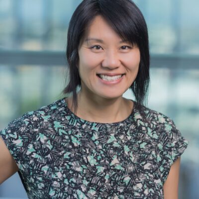 Professional photo of a woman smiling at the camera wearning a blue floral shirt