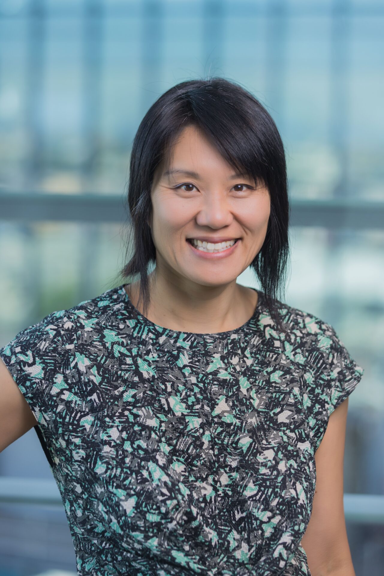 Professional photo of a woman smiling at the camera wearning a blue floral shirt