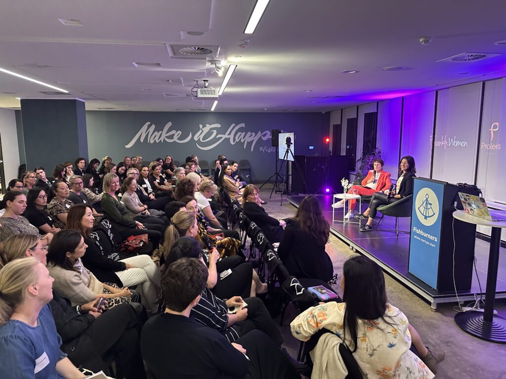 A photo of the room, showing the audience listening to the interview between Annette and Melina